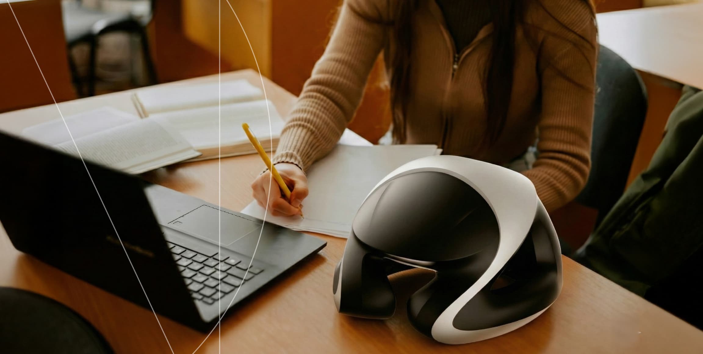 EEG headset on a desk beside a person writing at a laptop
